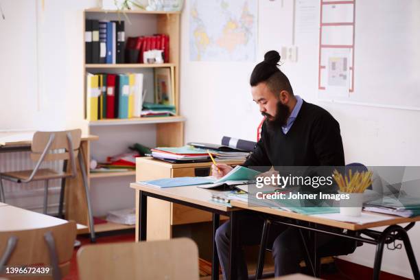 teacher working in classroom - teacher desk fotografías e imágenes de stock