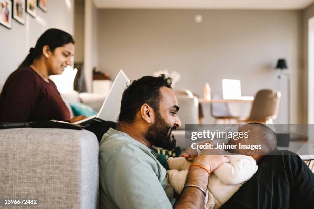 father and mother with baby in living room - indian living room stock-fotos und bilder