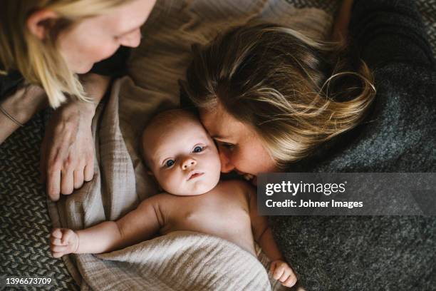 mothers lying in bed with newborn baby - lesbian bed stock pictures, royalty-free photos & images