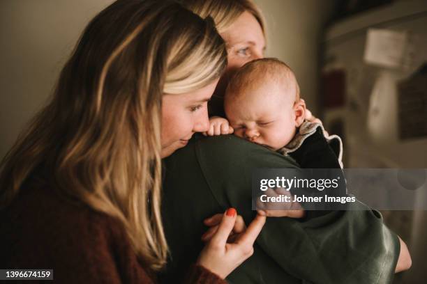 mothers holding sleeping newborn baby - parental leave stock pictures, royalty-free photos & images