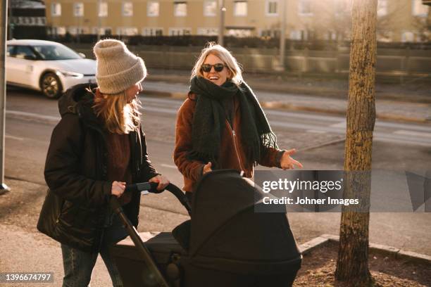 mothers walking with baby stroller along street - maternity leave stockfoto's en -beelden