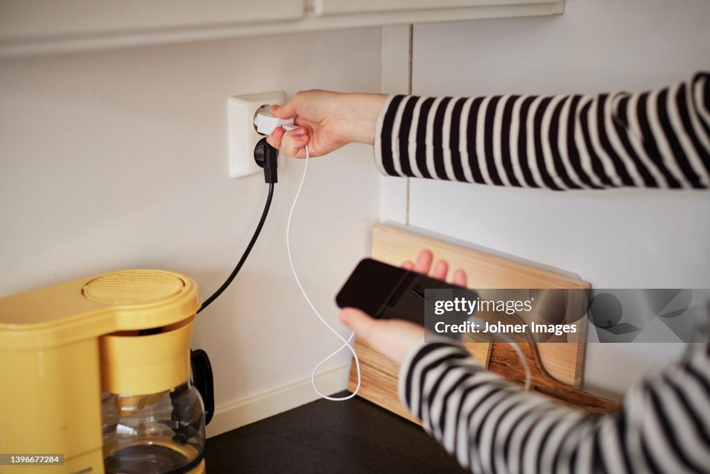 Hands plugging in cell phone charger