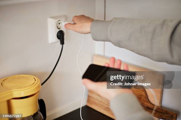 hands plugging in cell phone charger - power point stock pictures, royalty-free photos & images