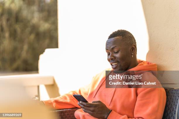 man using a mobile phone while sitting on a sofa outdoors. - familie sofa stock pictures, royalty-free photos & images