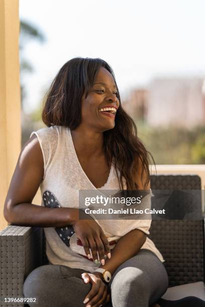 happy woman laughing while relaxing with friends sitting on a sofa outdoors at home. - familie sofa stock pictures, royalty-free photos & images