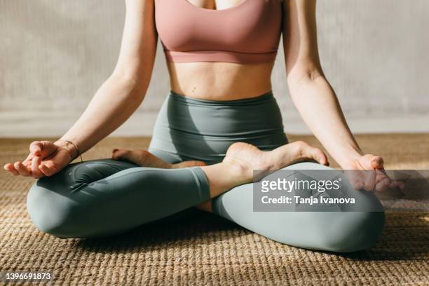 close-up young woman doing yoga at home. cropped image of a woman meditating in the lotus pose - lotus position stock pictures, royalty-free photos & images