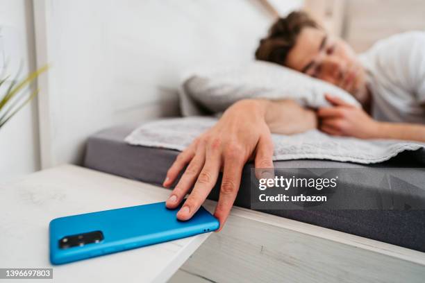 young man snoozing alarm on a smart phone - turning on or off imagens e fotografias de stock