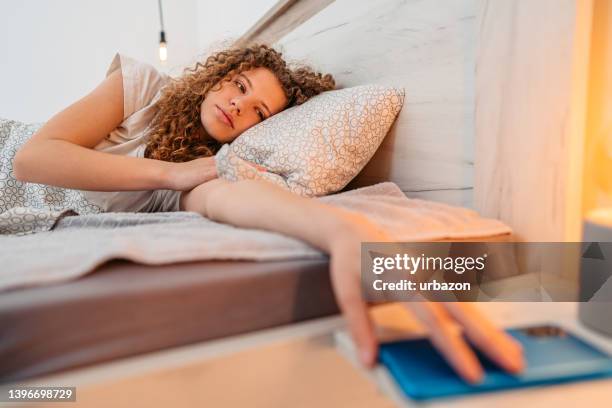 young woman snoozing alarm on a smart phone - overslept stock pictures, royalty-free photos & images