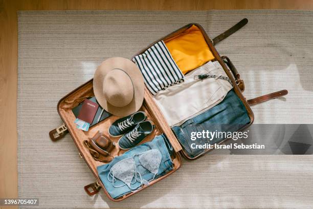 view from above of an open suitcase full of clothes ready to travel. - flatlay stock-fotos und bilder