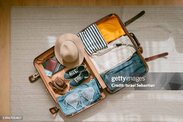 view from above of an open suitcase full of clothes ready to travel. - open suitcase stock pictures, royalty-free photos & images