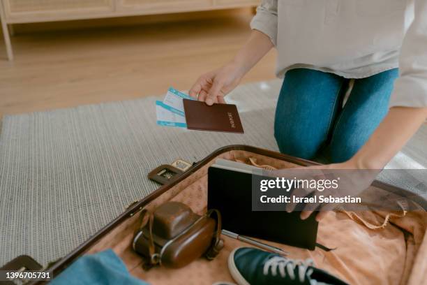 unrecognizable young woman checking passport, travel tickets and suitcase while preparing her vacation trip. - passport open stock pictures, royalty-free photos & images