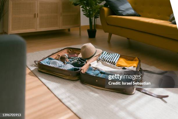 horizontal view of an open suitcase full of clothes ready to travel. - open travel bag stock-fotos und bilder