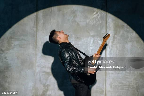 emotional man artist plays rock song on electric guitar and enjoys performing on stage. - cantante rock foto e immagini stock