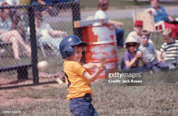 View of a young baseball player at he swings at a pitch during a Levittown Continental Little League game, Levittown, Pennsylvania, June 1970.