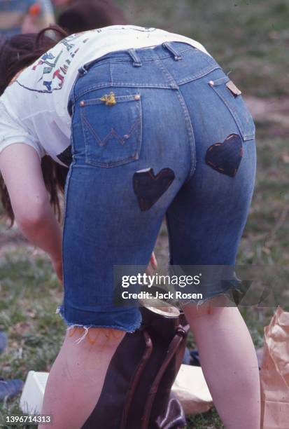 View, from behind of a woman as bends over, revealing heart-shaped patches on the back of her cut-off jeans, during the first Earth Day event,...