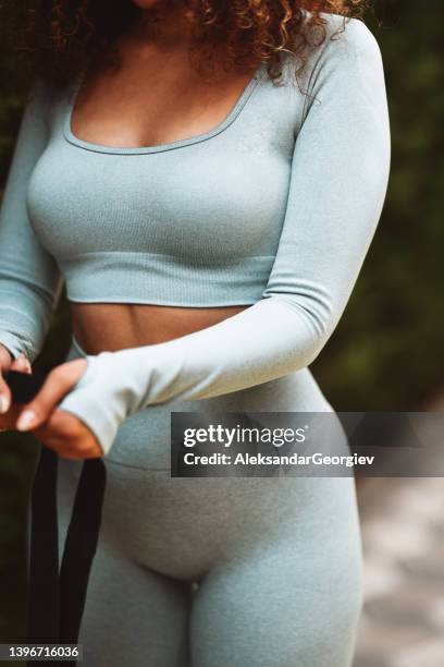 front view of fit female with curly hair holding rubber bands for workout - sportbeha stockfoto's en -beelden