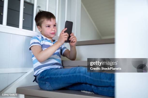 boy using mobile phone at home - carly simon signs copies of boys in the trees stockfoto's en -beelden