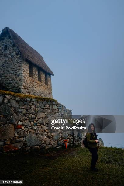 mujer turista con mochila mirando la cámara frente a las maravillosas ruinas de machu picchu - mirando a la cámara stockfoto's en -beelden