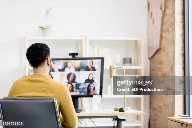 over-the-shoulder view unrecognizable man using desktop pc for meeting - telewerk stockfoto's en -beelden