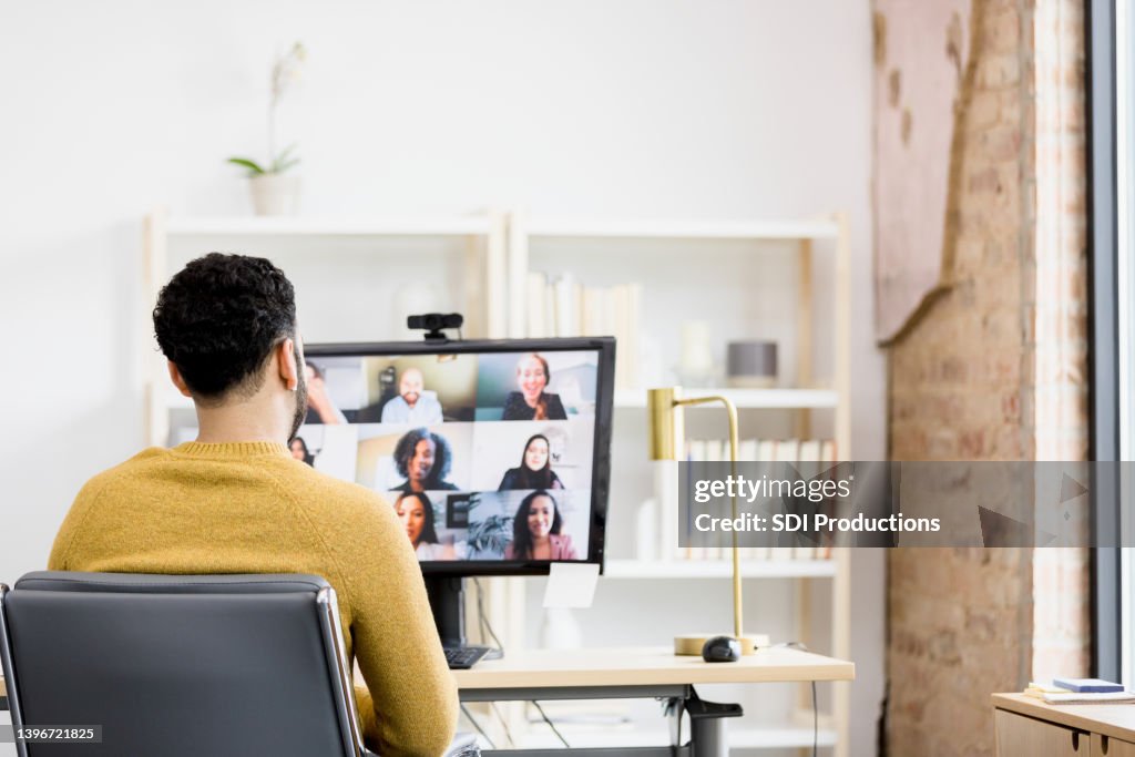 Visão over-the-shoulder homem irreconhecível usando PC desktop para reunião