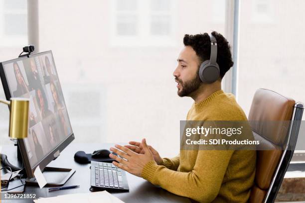 young man hot-desks to lead virtual team meeting - business woman side stockfoto's en -beelden