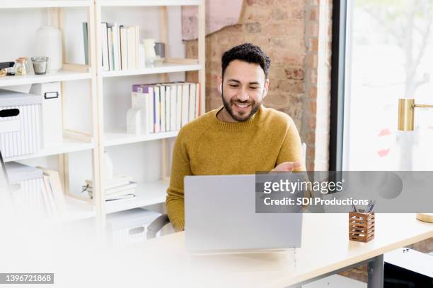 man uses laptop to video conference with friends - online review imagens e fotografias de stock