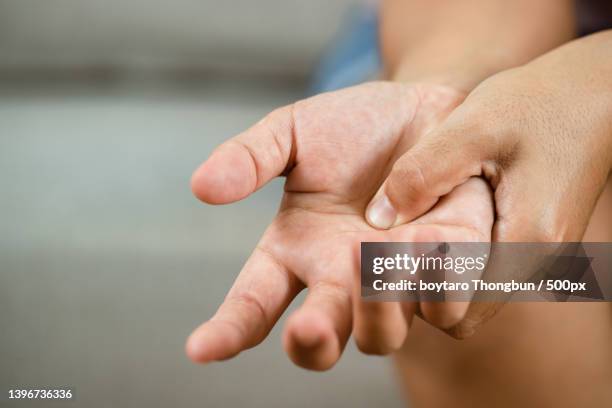 osteoarthritis concpet with cropped image of person with hand on hand - finger injury stock-fotos und bilder