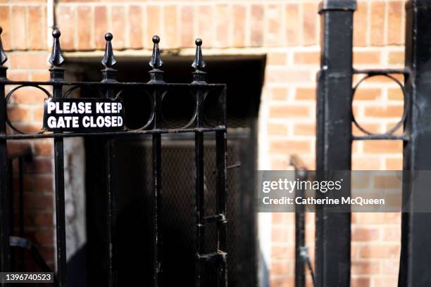 the irony: open iron gate with “please keep gate closed” sign affixed - crime prevention stock pictures, royalty-free photos & images