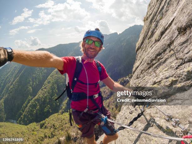 man taking selfie on a via ferrata route - rock climbing stock pictures, royalty-free photos & images