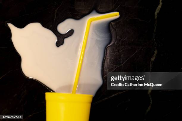 don’t cry over spilled milk: bright yellow cup & straw overturned on counter with milk splattered (partial view) - dont waste food 個照片及圖片檔