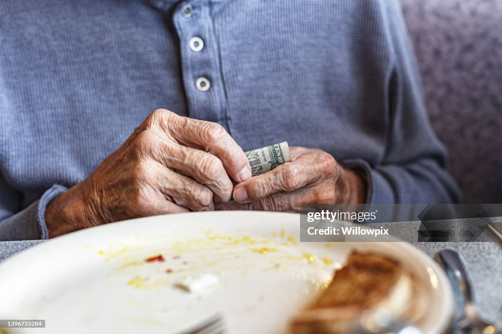 Elderly Man Holding Money To Pay For Restaurant Breakfast