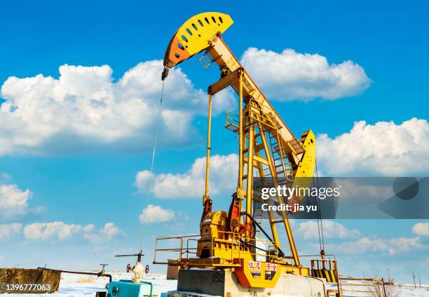 in winter, the oil extraction machine in the snow is working. xinjiang province, china. - oil geology stock pictures, royalty-free photos & images