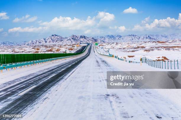 in winter, the highway leading to the mountains in the wilderness. xinjiang province, china. - sinkiang province stock pictures, royalty-free photos & images