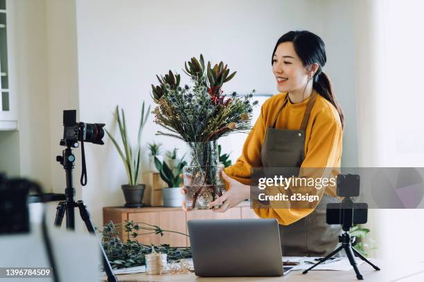 professional young asian female florist making vlog session on flower bouquet arrangement class with laptop and camera at home. self-employment. online classes. small business concept - filming tutorial stock pictures, royalty-free photos & images