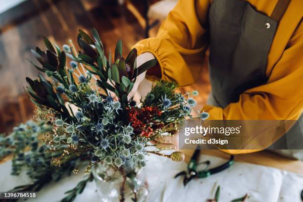 cropped shot of young asian woman arranging freshly cut flowers in a vase at home. leisure, hobbies and lifestyle concept - florest stock pictures, royalty-free photos & images