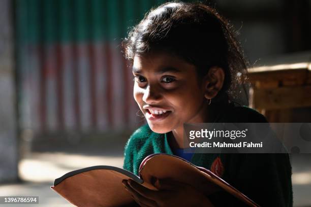 a village girl is reading book with a smile - bangladesh stock-fotos und bilder