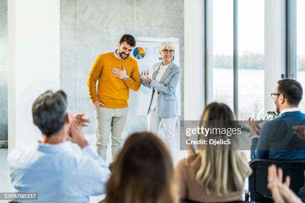 large group of happy business people applauding and congratulating a young man. - gratitude stock pictures, royalty-free photos & images