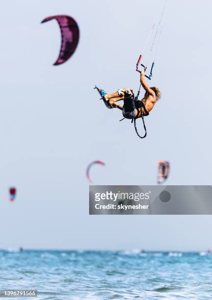 unbeschwerter mann, der beim kiteboard-surfen auf see springt. - kite surf stock-fotos und bilder