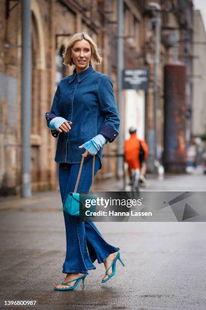 Suzy Eskander wearing denim shirt and flare jeans, blue leather bag and Bottega Veneta blue strap heels at Afterpay Australian Fashion Week 2022 on...