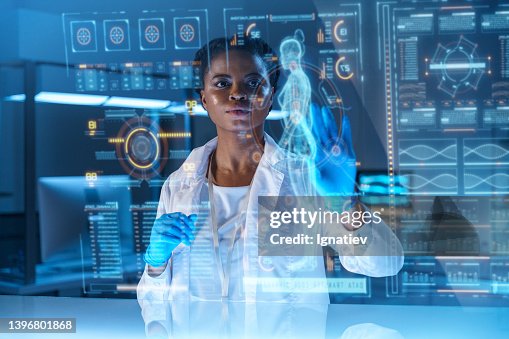 A young African - American doctor works on HUD or graphic display in front of her A young African - American doctor works on HUD or graphic display in front of her