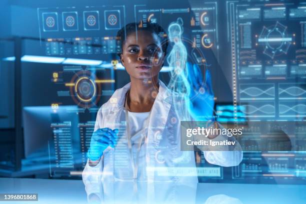 a young african - american doctor works on hud or graphic display in front of her - hud graphic imagens e fotografias de stock