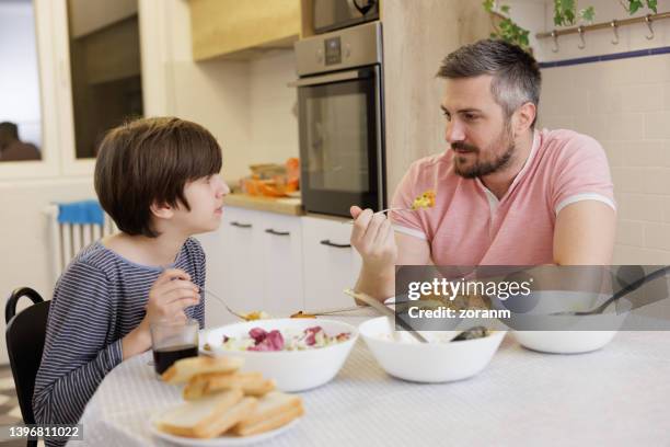 man celebrating father's day at home with his son, having lunch together - fathers day lunch stock pictures, royalty-free photos & images