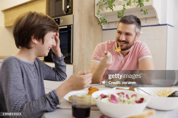 man sitting at the dining table and celebrating father's day with his son - fathers day lunch stock pictures, royalty-free photos & images