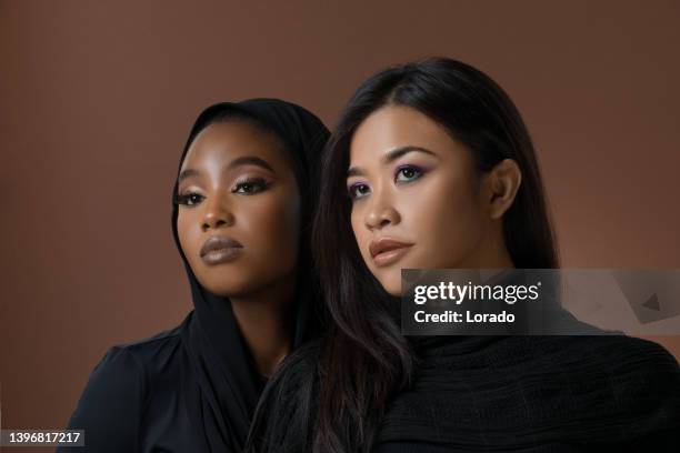 two beautiful muslim women of differing ethnicity in a studio shot - modest clothing stock pictures, royalty-free photos & images