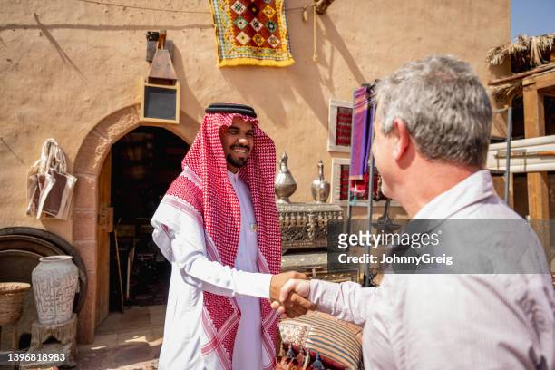 zu besuch geschäftsmann, der sich mit einem händler aus dem nahen osten verbindet - saudiarabien stock-fotos und bilder
