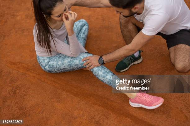 young man massaging woman's injured leg - dislocation stock pictures, royalty-free photos & images