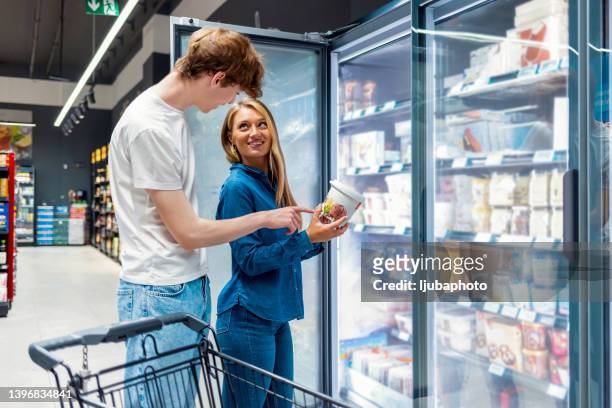 couple choosing ice cream at the store - frozen food supermarket stock pictures, royalty-free photos & images