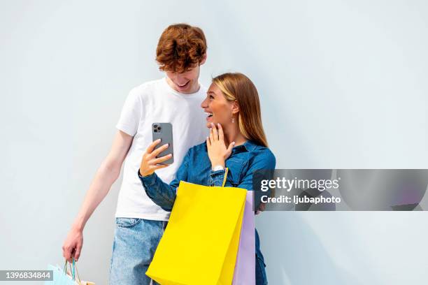 happy couple using app on their cell phone at the shopping center - shopping centre ad stock pictures, royalty-free photos & images