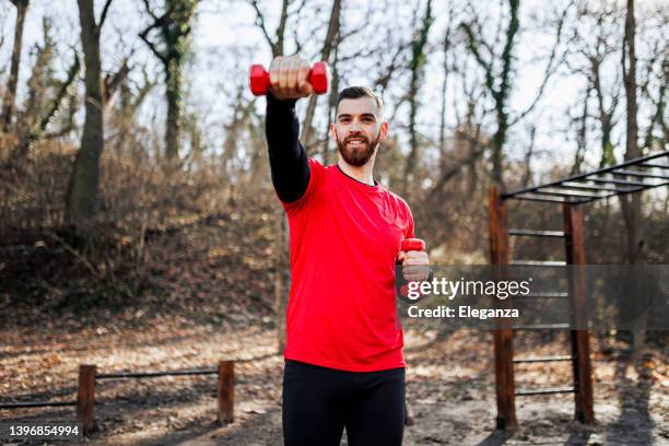 fit man exercising with weights outdoors - man dumbbell stock pictures, royalty-free photos & images