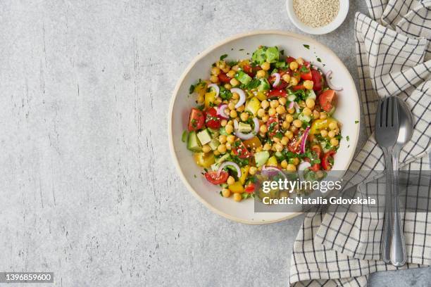 mediterranean salad of chopped cherry tomatoes, canned sweet corn, sesame seeds, red onion, sliced cucumbers, parsley. healthy dash diet eating. balanced food for vegetarians. overhead, horizontal, copy space, served in buddha bowl, napkin and tableware - buddha bowl stockfoto's en -beelden